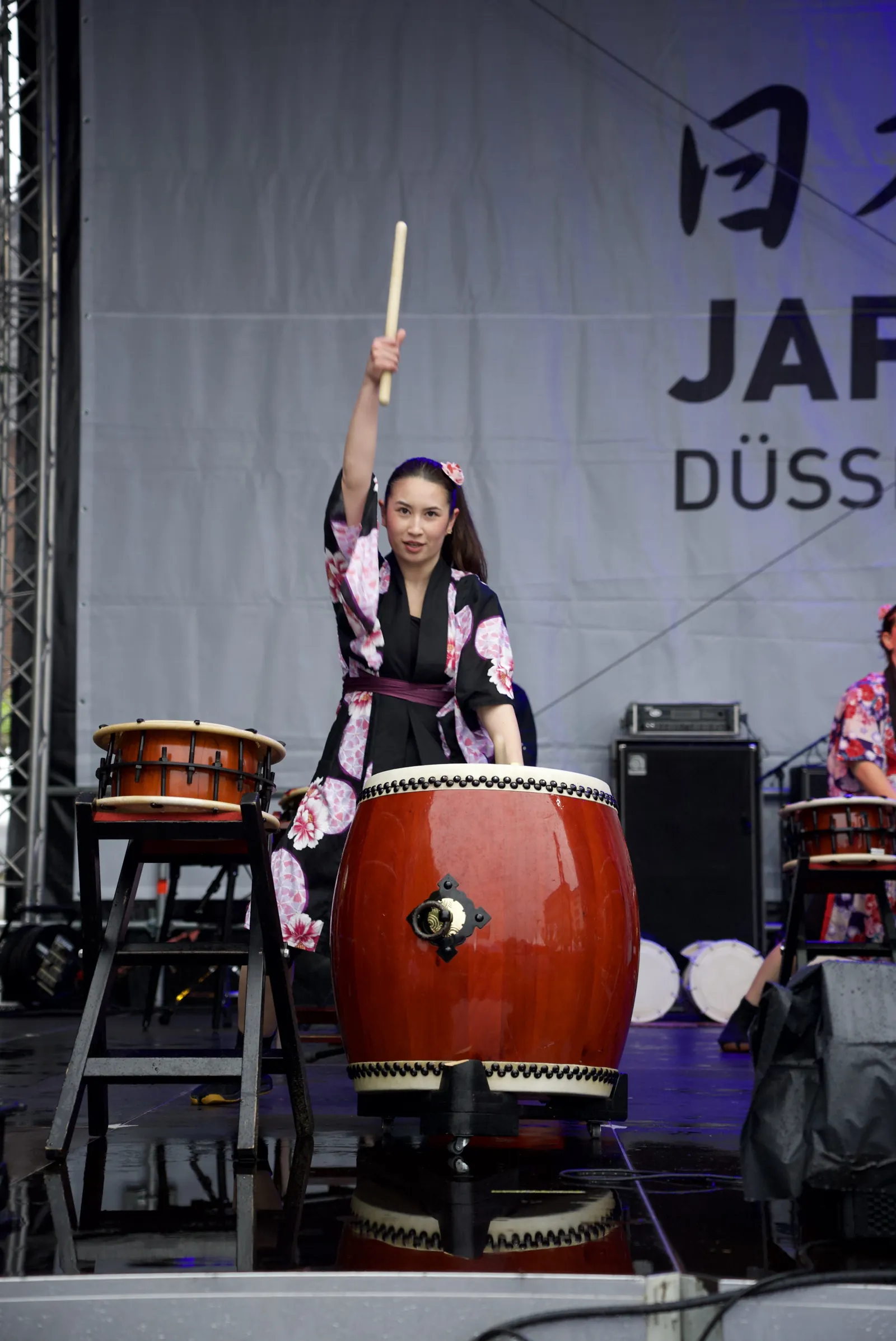 Yumi at her taiko drum with her drumstick raised